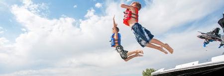 Boys jumping into lake from boat